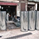 Ironsmiths assemble large iron containers for wheat storage at their workplace in the provincial capital