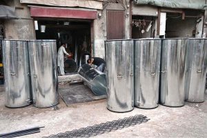 Ironsmiths assemble large iron containers for wheat storage at their workplace in the provincial capital
