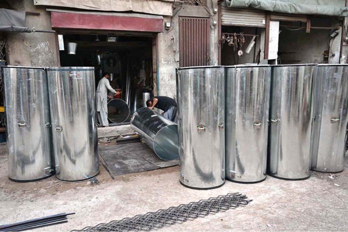 Ironsmiths assemble large iron containers for wheat storage at their workplace in the provincial capital