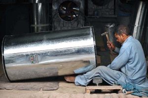 Ironsmiths assemble large iron containers for wheat storage at their workplace in the provincial capital
