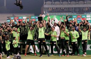Lahore Qalandars players pose for a group photo as their captain, Shaheen Shah Afridi, lifts the trophy after winning the PSL-X T20 Final against Quetta Gladiators at Gaddafi Stadium..