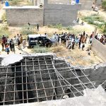 A view of residents gathers as police personnel inspect the site where Pakistan shot down an Indian drone in the catchment of the city