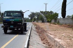 CDA worker busy in watering plants while sitting on the water tanker on green belts at Club road