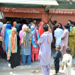 A large number of eligible women queue outside a mobile communication shop in Latifabad to receive cash assistance under the Benazir Income Support Program (BISP)