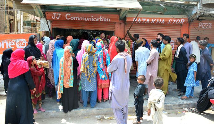 A large number of eligible women queue outside a mobile communication shop in Latifabad to receive cash assistance under the Benazir Income Support Program (BISP)