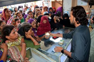 A large number of eligible women queue outside a mobile communication shop in Latifabad to receive cash assistance under the Benazir Income Support Program (BISP)