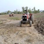 A farmer preparing land for next crop with help of tractor along Lahore Road