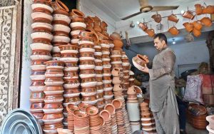 A vendor arranges and displays clay made pots in his shop to attract the customers at Bara Bazaar.