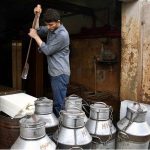 A worker removes a block of milk ice from the box after the milk stored in it to prevent spoilage before delivery at the local ice factory.
