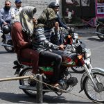 A motorcyclist covers his face with a scarf to shield against the soaring summer temperatures in the Provincial Capital