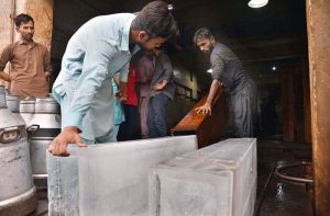 A worker removes an ice block from the ice box after preparation for delivery at the local ice factory.
