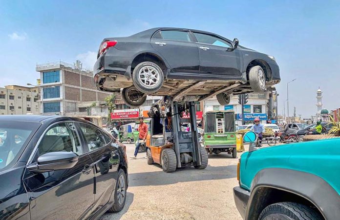 A traffic police officer using a lifter to remove a wrongly parked vehicle in the Saddar area of the city