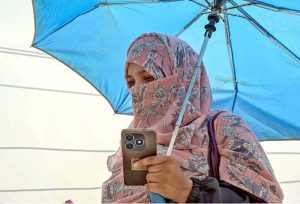 A woman shields herself with an umbrella to escape the blazing sun as extreme heat grips the federal capital