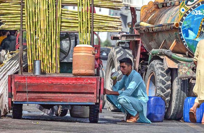 A man enjoys a glass of sugarcane juice to quench his thirst and beat the scorching heat in the federal capital