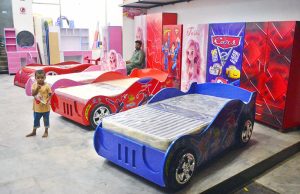 A vendor displaying the furniture for children to attract the customers at his shop in a local market.