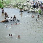 Youngsters enjoy bathing at Rawal Dam spillways in the Federal Capital.