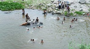 Youngsters enjoy bathing at Rawal Dam spillways in the Federal Capital.