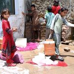 Young girls carry water coolers after filling from an ice factory's filtration plant during hot weather in the city