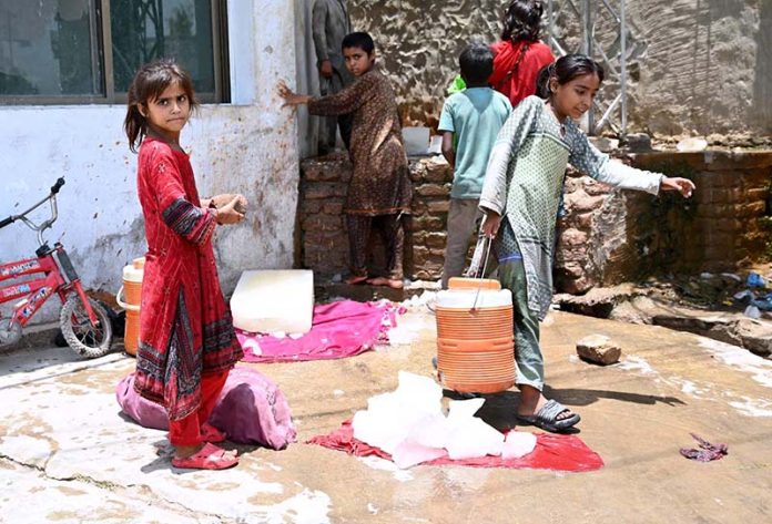 Young girls carry water coolers after filling from an ice factory's filtration plant during hot weather in the city