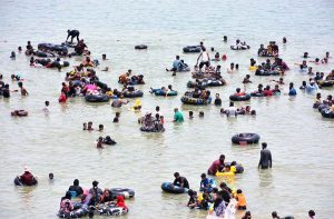 Large number of people enjoy bathing to get relief from scorching hot weather at Keenjhar Lake.