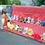 A vendor arranging and displaying toys to attract the customers at his setup in the Provincial Capital