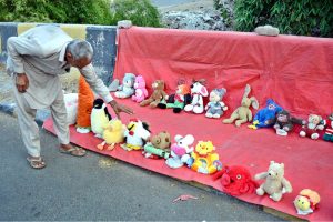 A vendor arranging and displaying toys to attract the customers at his setup in the Provincial Capital