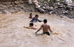 A group of youngsters bathing in water pond to get some relief from scorching hot weather in Federal Capital.