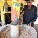 A young vendor preparing traditional summer drink (thadal) to attract the customers at roadside setup during hot weather in the city
