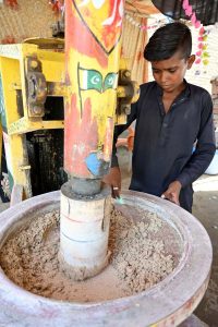 A young vendor preparing traditional summer drink (thadal) to attract the customers at roadside setup during hot weather in the city