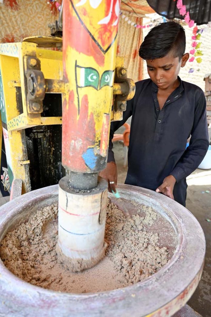 A young vendor preparing traditional summer drink (thadal) to attract the customers at roadside setup during hot weather in the city