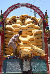 Labourers busy in unloading sacks of flour from a delivery truck.