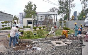 Labourers engage in construction work in front of the Nawaz Sharif Institute of Cardiology