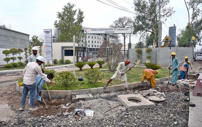 Labourers engage in construction work in front of the Nawaz Sharif Institute of Cardiology