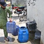 A person filling pots with water from water filtration plant