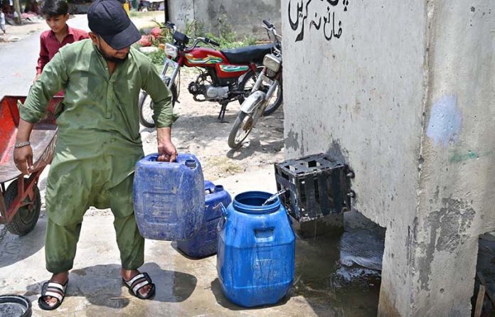A person filling pots with water from water filtration plant