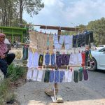 A female vendor sits by the roadside waiting for customers to sell arm sleeves during hot weather along Islamabad Expressway