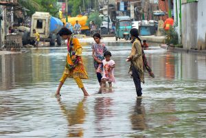 Girls passing through rain water accumulated on the road after heavy rain in the city at Makki Shah Road.
