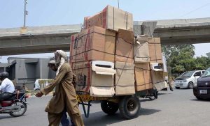 An elderly man pulls an overloaded cart with his full force through Raja Bazaar to earn a livelihood for his family under burning sun as temperatures soar in the city