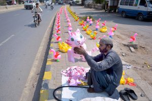 Vendor displaying plastic toys on footpath to attract customers.