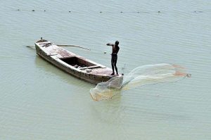 A fisherman throwing net into the Indus river for catching the fishes.