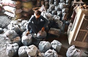 A shopkeeper displays and sells packets of charcoal for barbecue preparations ahead of Eid al-Adha at his shop in a local market.
