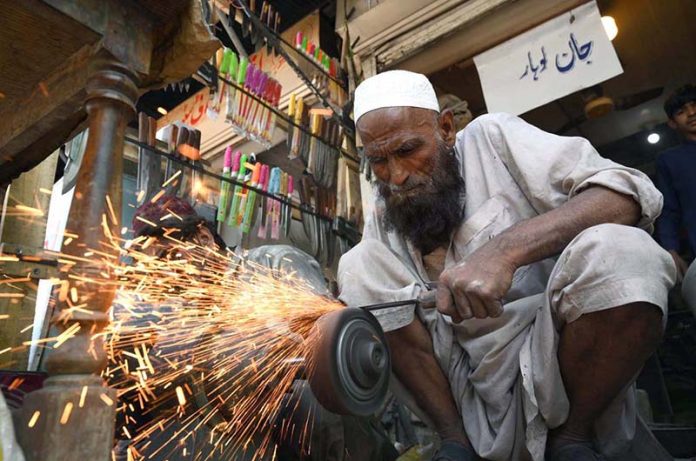 Blacksmith busy sharpening knives to be used for slaughtering sacrificial animals in connection with Eidul Azha