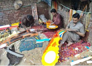 Workers are busy preparing decorative materials for buses and trucks at their workplace.