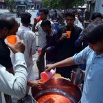 Volunteers distributing traditional summer drink among people during hot day in the city