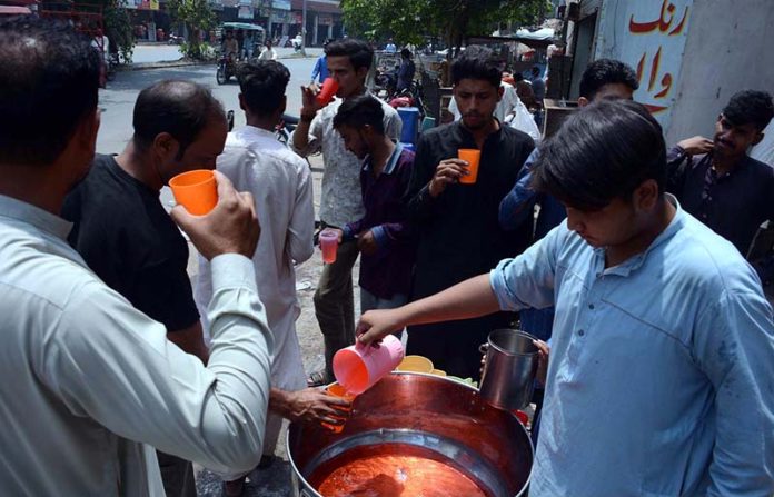 Volunteers distributing traditional summer drink among people during hot day in the city