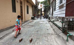 Children are playing cricket in a street.