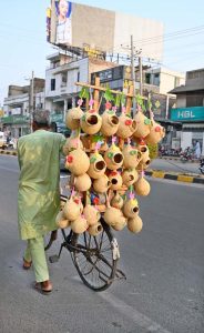 A street vendor sells handmade bird nests on his bicycle while strolling on College Road in the city