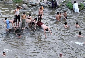 Youngsters enjoy bathing in Korang Nallah near Chak Shahzad to seek relief from the extreme heatwave gripping the Federal Capital.