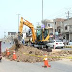 Labourers are digging on road with help of machine for the repairing of sui gas pipeline near Rasheedabad