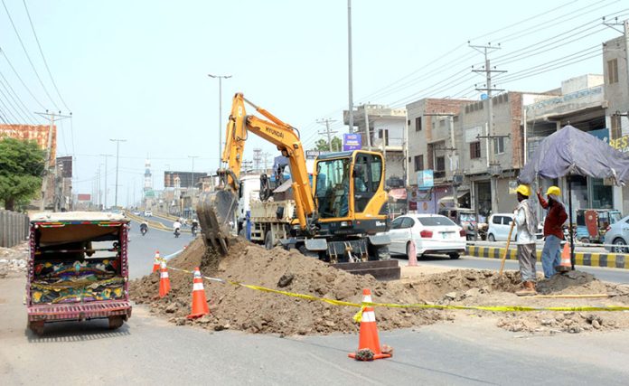 Labourers are digging on road with help of machine for the repairing of sui gas pipeline near Rasheedabad